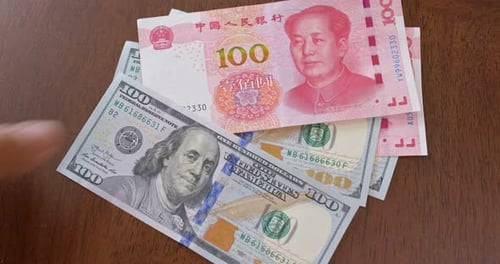 Dollar Bills and Yuan Notes Stacked on Table