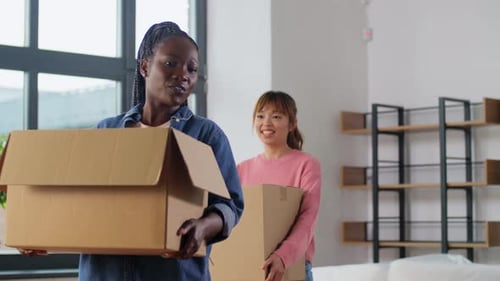 Two Women Moving Boxes Into New Home