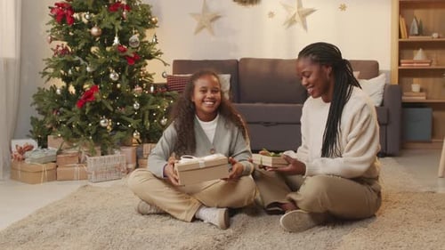 Family Opening Gifts Beside Christmas Tree in Living Room