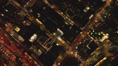 Cars Driving on Street Between High Rise Buildings in Night City