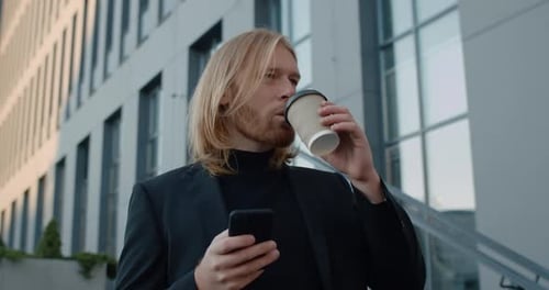 Bottom View of Handsome Businessman Drinking Coffee From Paper Cup and Using Smartphone. Bearded Man