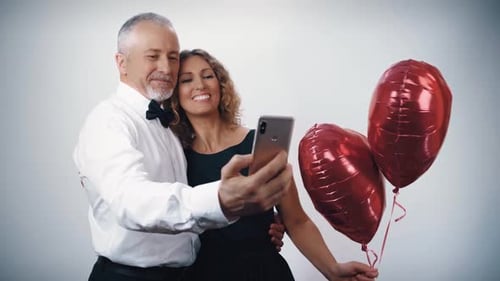 Happy Couple Smiling and Taking Selfie with Balloons