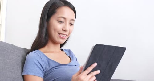Woman Relaxes on Couch Using Tablet Device