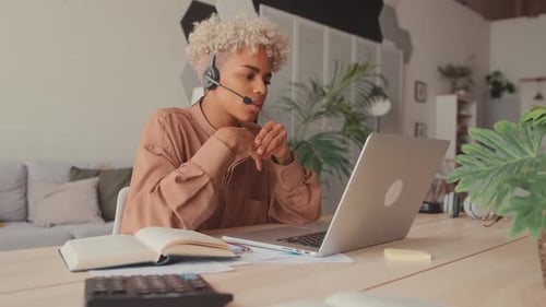 Afrikanische Studentin trägt Headset mit Blick auf Laptop Online-Webinar