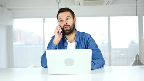 Man Working, Answering Phone Call in Bright Office