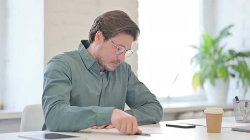 Man Writting at Desk and Crumpling Paper