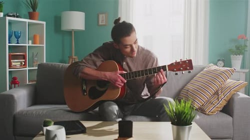 Man Plays Guitar and Sings at Home