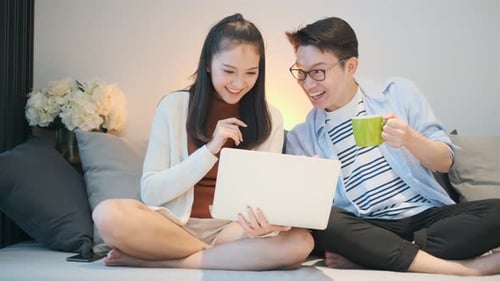 Happy Young Couple Using Laptop at Home Together