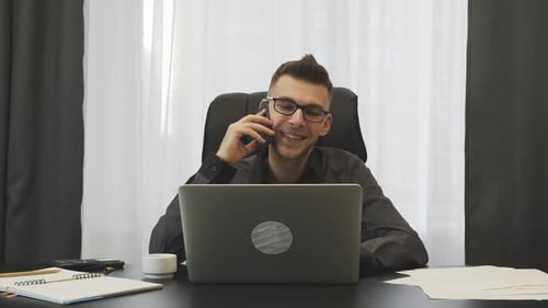Happy businessman talks on phone in modern office