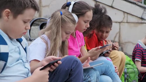 Children Using Technology Outdoors on School Steps