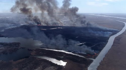 Wildfires, Large Fire Fast Moving By Dry Meadow with Smoke Going Up To Sky Near River, Drone View