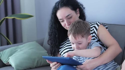 Woman Showing Child How to Use Tablet Indoors