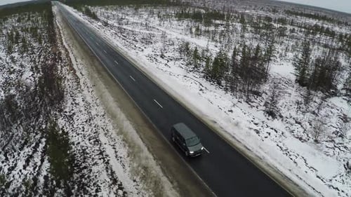 Aerial view of minivan driving winter road