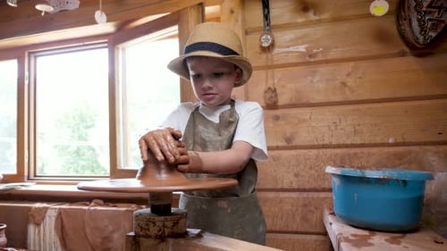 Young Boy Works with Clay on Pottery Wheel