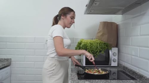 Smiling Woman Cooking Vegetables in Kitchen
