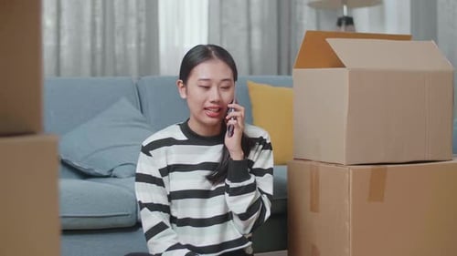 Woman Talking on Cellphone Surrounded by Moving Boxes