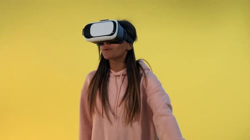 Young Woman Using VR Headset Against Yellow Background