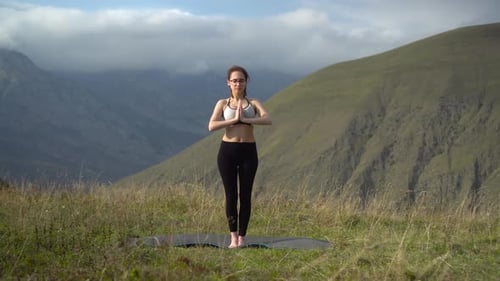 Young Woman in Tracksuit Practices Yoga Performing Mountain Pose in the Mountains. The Camera Moves