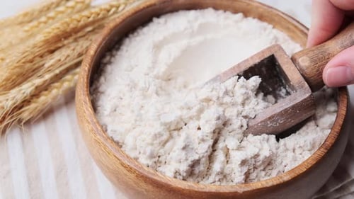 Pour wheat flour from wooden bowl.