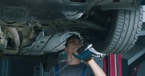 Young Mechanic Examining Car in Maintenance Service, Making Suspension Test in Garage