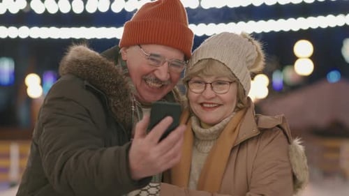 Smiling Senior Couple Looks at a Phone