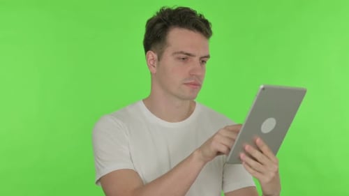 Junger Mann nutzt digitales Tablet auf grünem Hintergrund