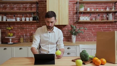 Person Using Tablet in Bright Kitchen with Apple