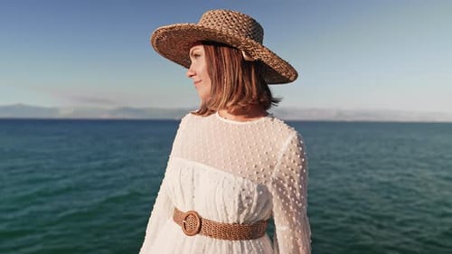 Retrato de mulher elegante em vestido branco posando na praia de Cliff, perto do mar Mediterrâneo