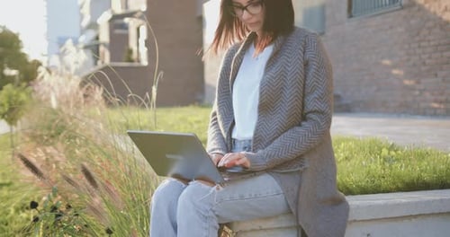 Woman Working on Laptop in Urban Outdoor Setting
