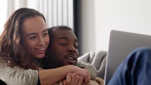 Loving Couple Watching Laptop Together on Sofa