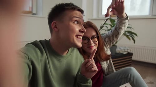 Smiling Couple Taking Video in New Home With Keys