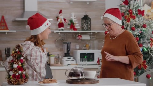 Grandmother and Granddaughter Exchanging Christmas Gifts in Kitchen