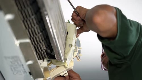Air Conditioner Repairman Using Screwdriver for Maintenance