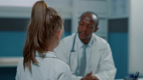 Doctor Consults with Young Patient in Hospital Office