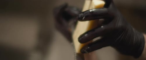 Italian Chef in black gloves grating parmesan cheese. Close up, slow motion.