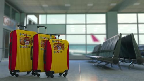 Spanish Flag Suitcases Rotating in Airport Terminal