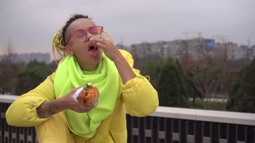 Woman with Colorful Hair Eats Sandwich Outdoors