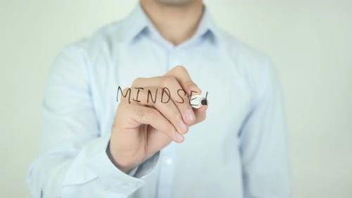 Man Writes Mindset on Clear Surface with Marker