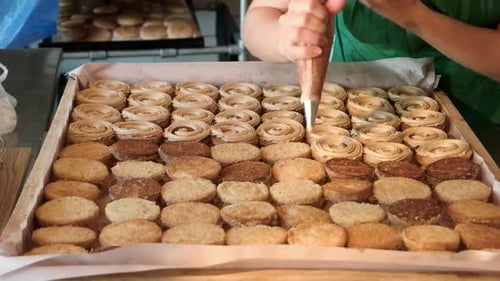 Baker Filling Cookies with Icing in Tray