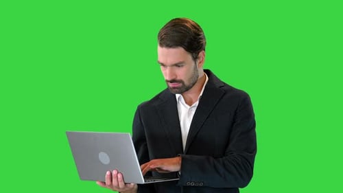 Young Standing Business Man Working on a Laptop on a Green Screen Chroma Key