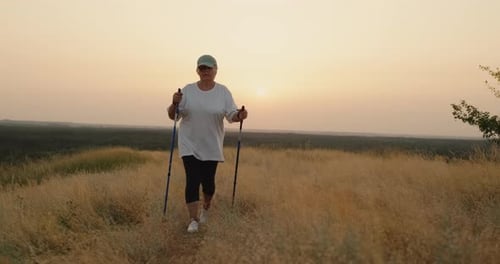 Woman Hiking in Field with Hiking Poles at Sunrise