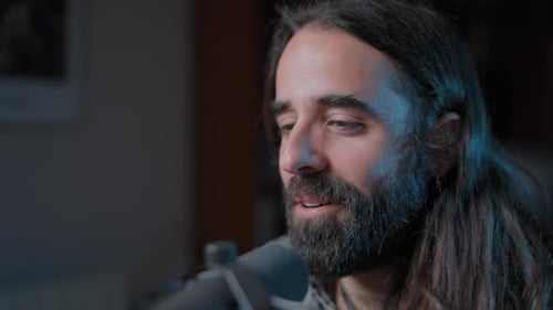 Man with Long Hair Speaking Into Microphone