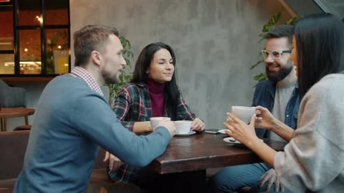 Happy Friends Girls and Guys Celebrating Reunion in Cafe Over Drinks Clanging Cups Sharing News