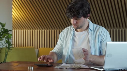 Smiling Young Man Analyzing His Expenses and Paying Online