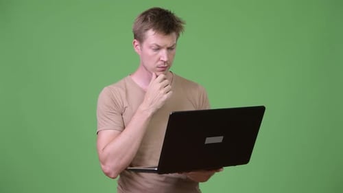 Young Handsome Scandinavian Man Thinking While Using Laptop