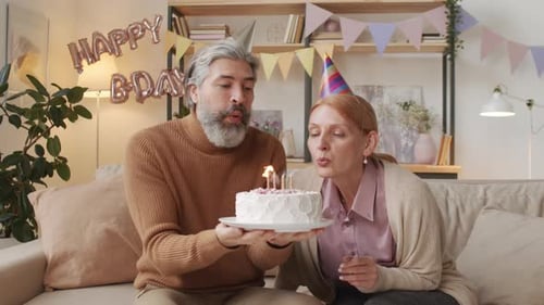 Happy Couple Blowing Out Birthday Cake Candles