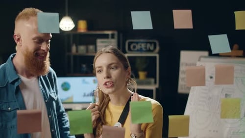 Businesswoman and Male Colleague Analyzing Brainstorm Notes in Hipster Office.
