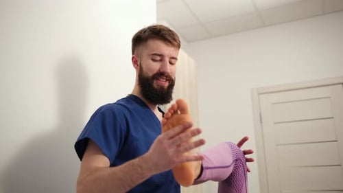 Bearded Man Examining Woman's Foot in Office
