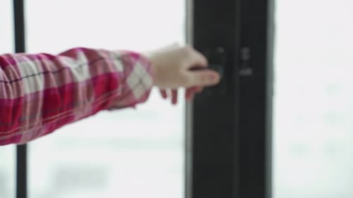 A Woman's Hand Closes the Black Window in the Kitchen