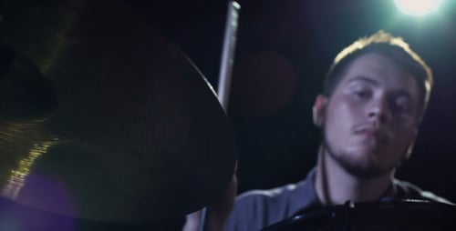 Drummer Plays Cymbal in Darkly Lit Performance